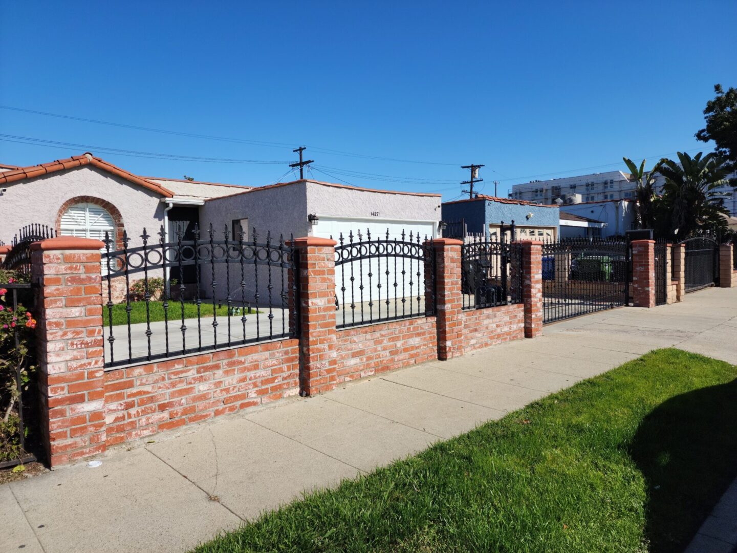 A brick wall with metal fence and grass